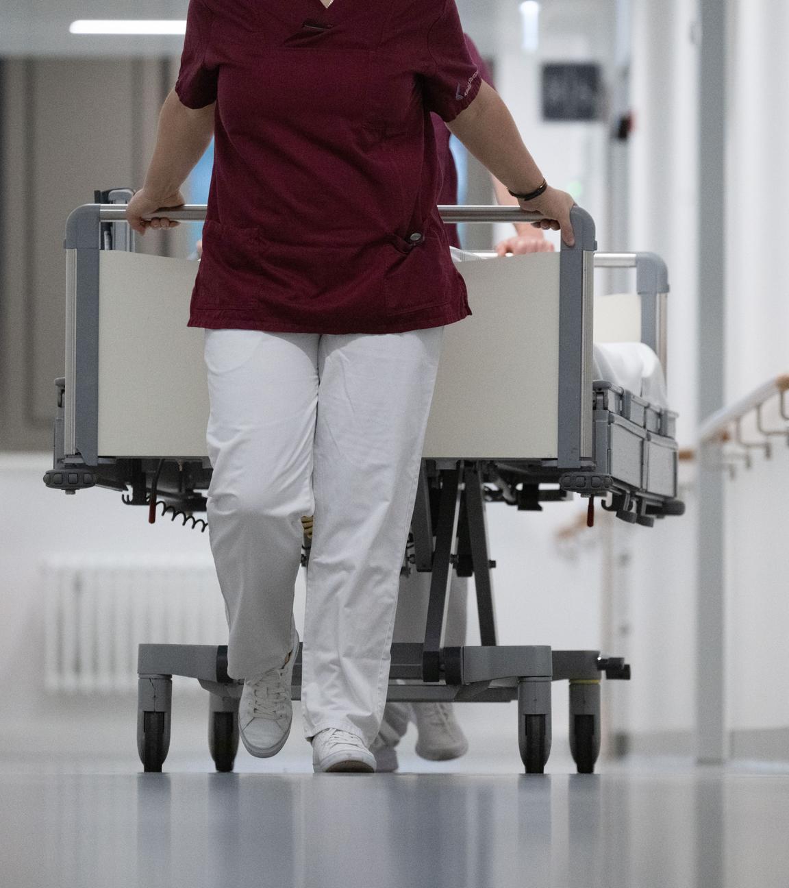  Eine Krankenpflegerin und ein Krankenpfleger schieben ein Krankenbett durch den Gang 