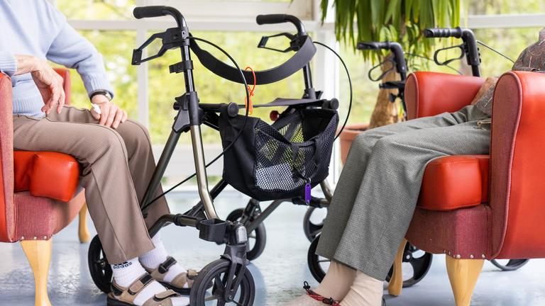 Zwei Bewohnerinnen eines Altenheims sitzen neben ihren Rollatoren.