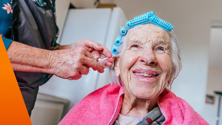 Ältere Frau bekommt Lockenwickler und lacht