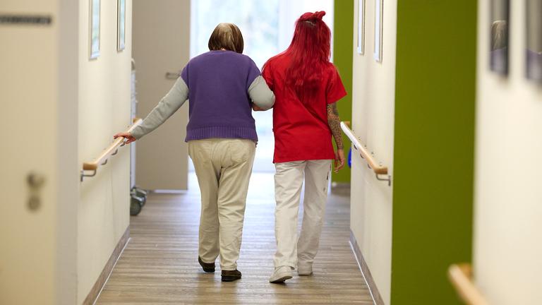 Eine Pflegekraft begleitet im DRK-Pflegezentrum Solferino eine Seniorin durch den Flur.