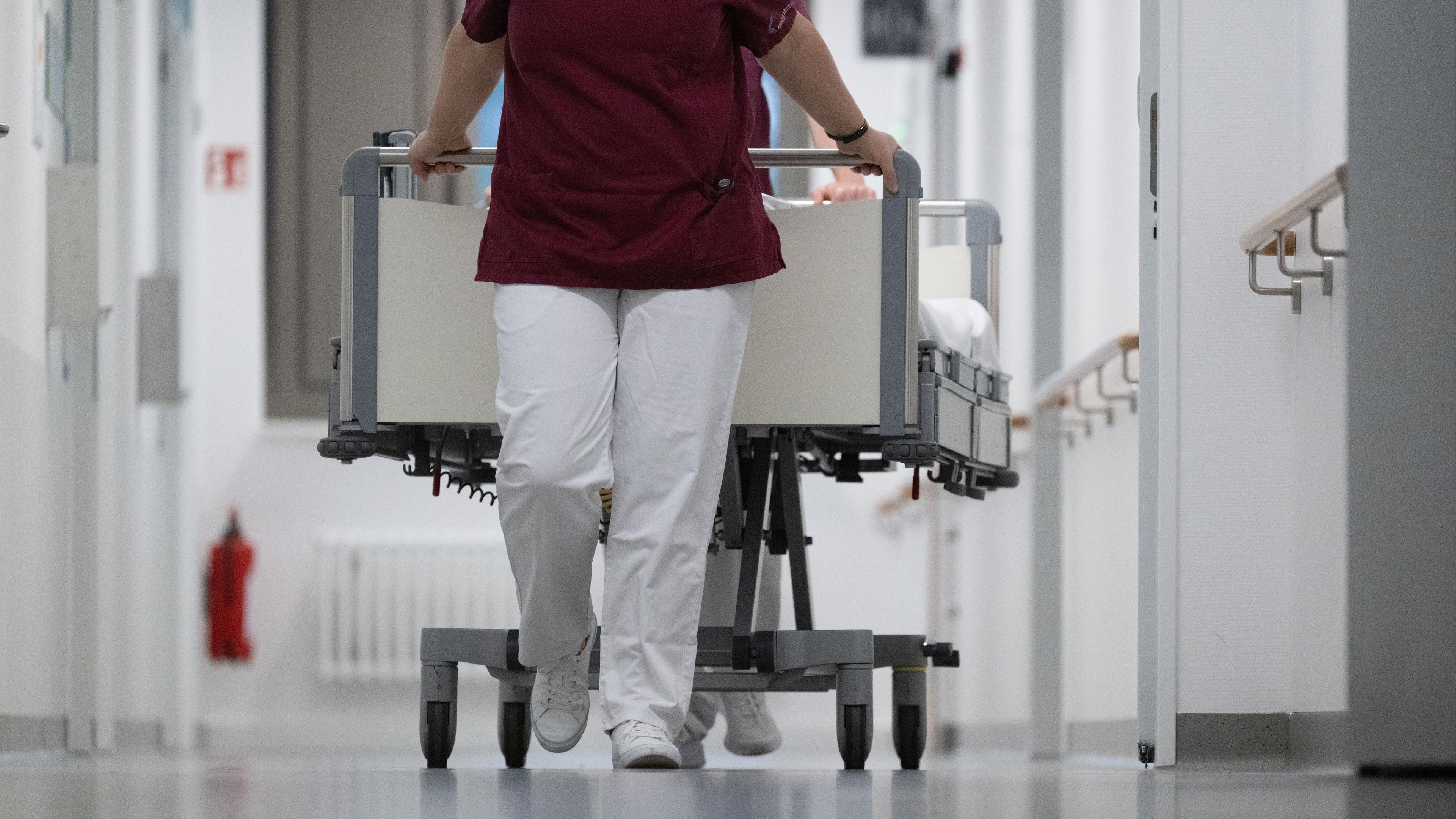 Pflegekraft zieht ein Krankenbett durch den Gang eines Krankenhauses