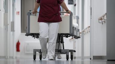 Pflegekraft zieht ein Krankenbett durch den Gang eines Krankenhauses