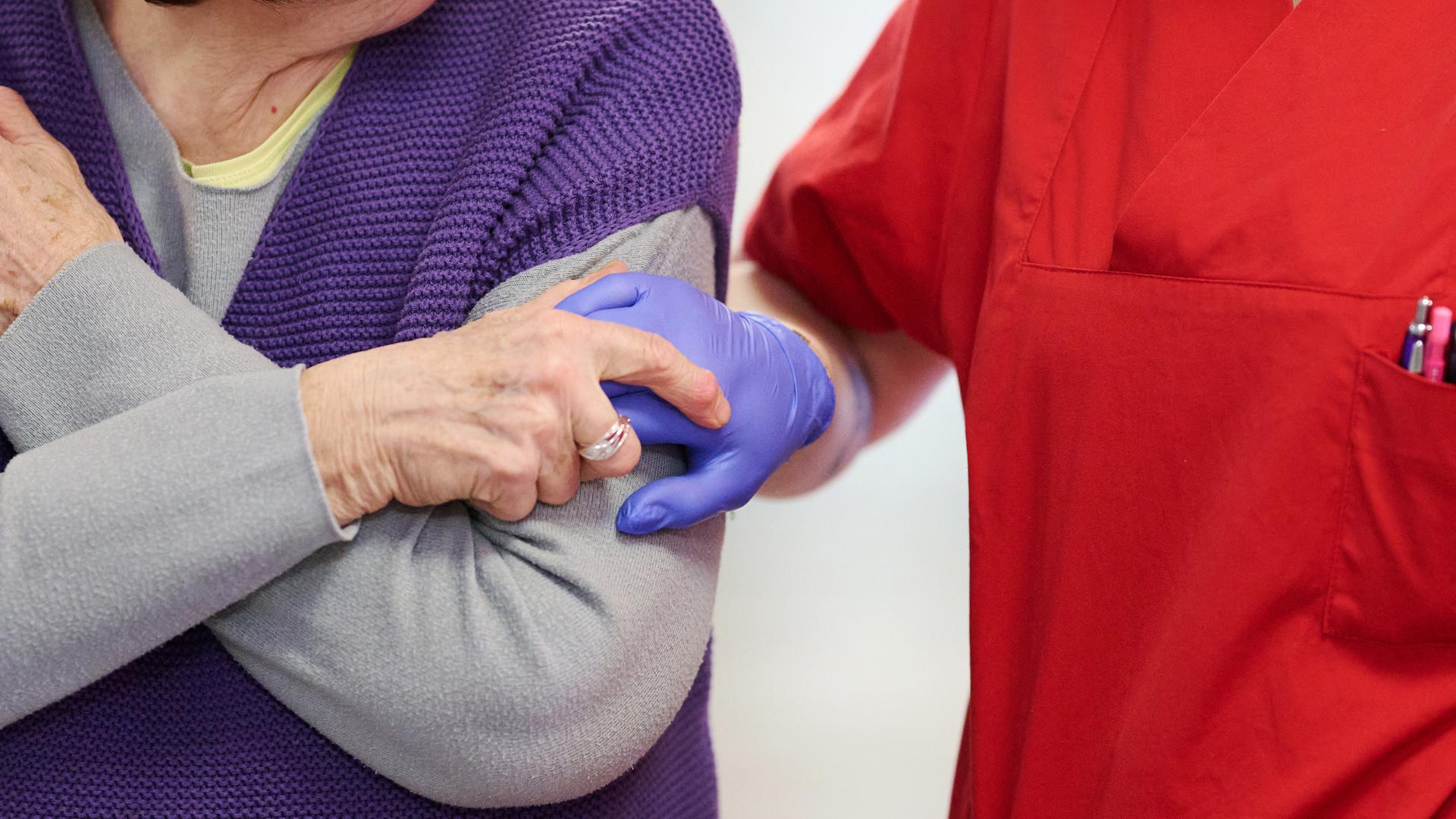 Pflegekraft nimmt Bewohnerin an der Hand.