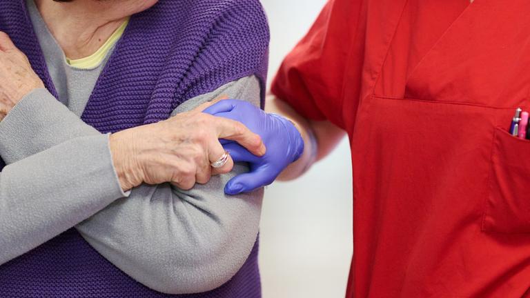 Pflegekraft nimmt Bewohnerin an der Hand.