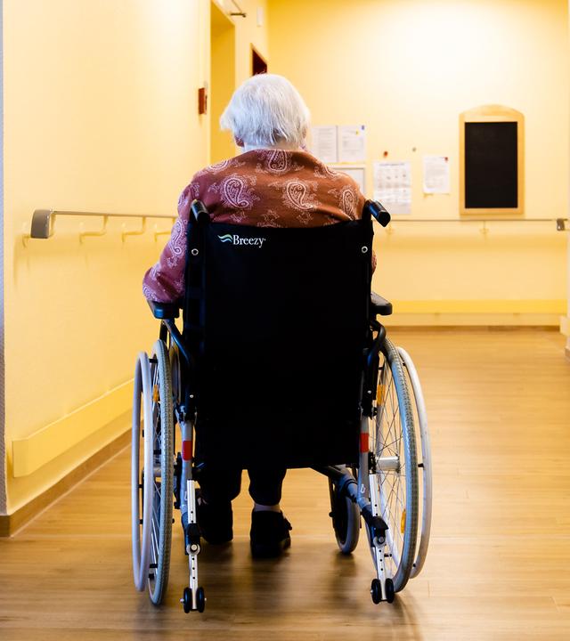 Eine Bewohnerin der Pflegestation sitzt in ihrem Rollstuhl (Archivbild)