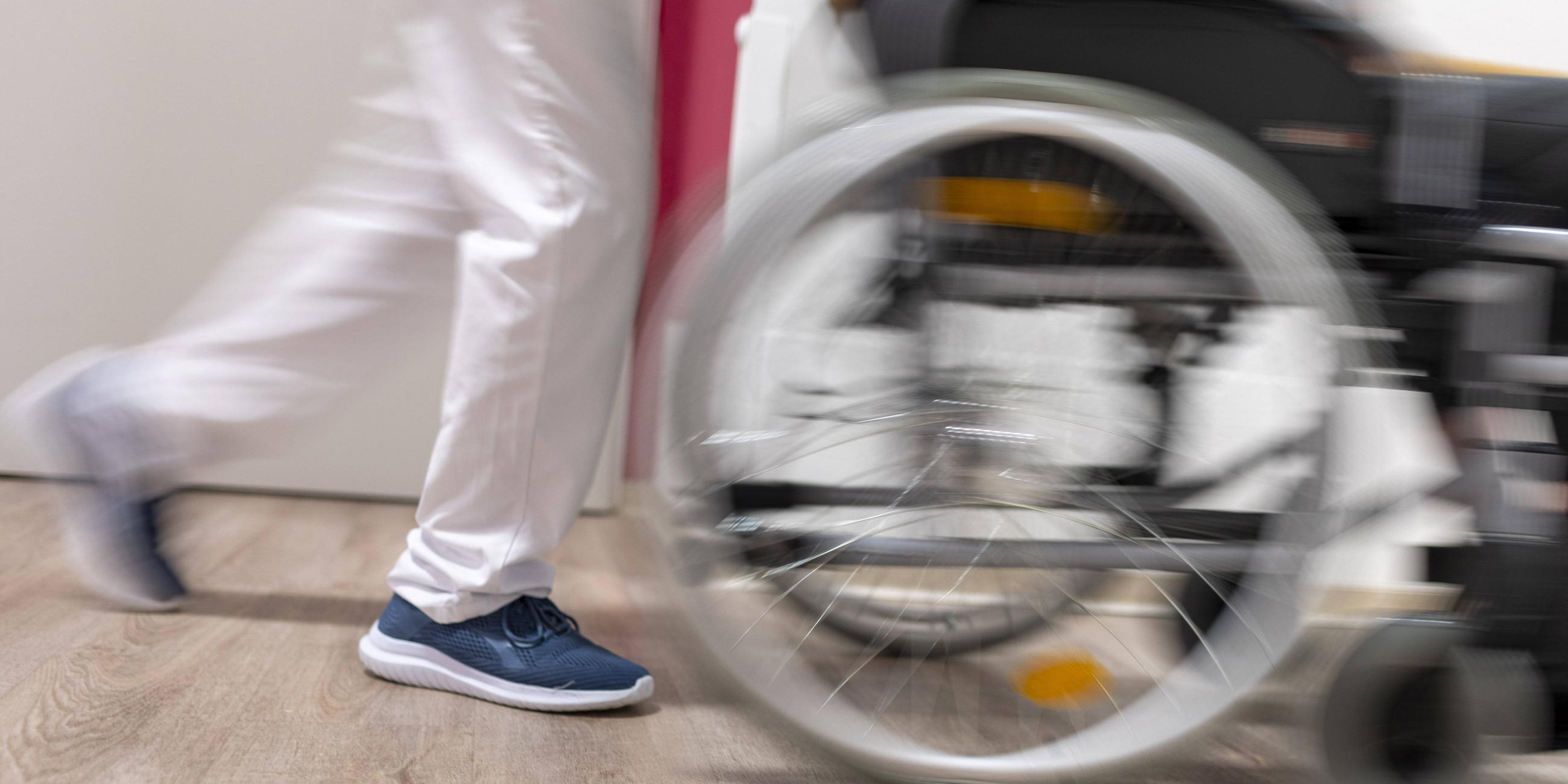 Archiv: Altenpfleger schiebt einen Rollstuhl im Pflegeheim 