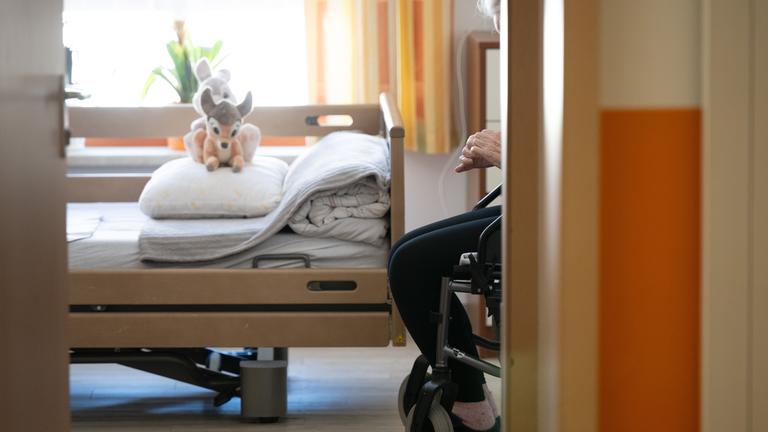 Ein Bewohner sitzt in einem Altenheim in seinem Zimmer in einem Rollstuhl. 