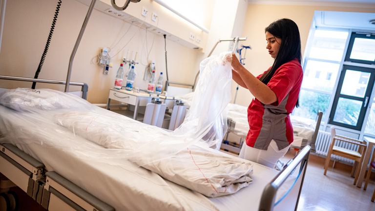 Eine ausländische Pflegerin neben einem Pflegebett.