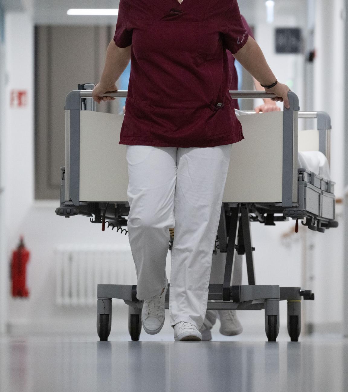 15.05.2024, Baden-Württemberg, Stuttgart: Eine Krankenpflegerin und ein Krankenpfleger schieben ein Krankenbett durch den Gang einer Station eines Krankenhauses.
