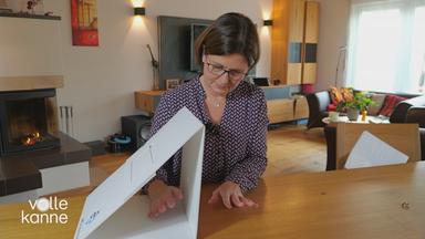 Eine Frau hält eine Hand neben eine Art Karton und die andere Hand (bei der die Extremitäten nicht mehr völlig vorhanden sind) in den Karton