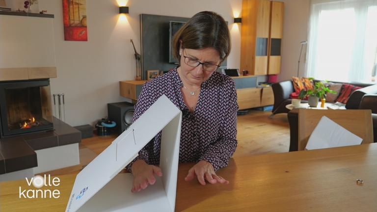 Eine Frau hält eine Hand neben eine Art Karton und die andere Hand (bei der die Extremitäten nicht mehr völlig vorhanden sind) in den Karton