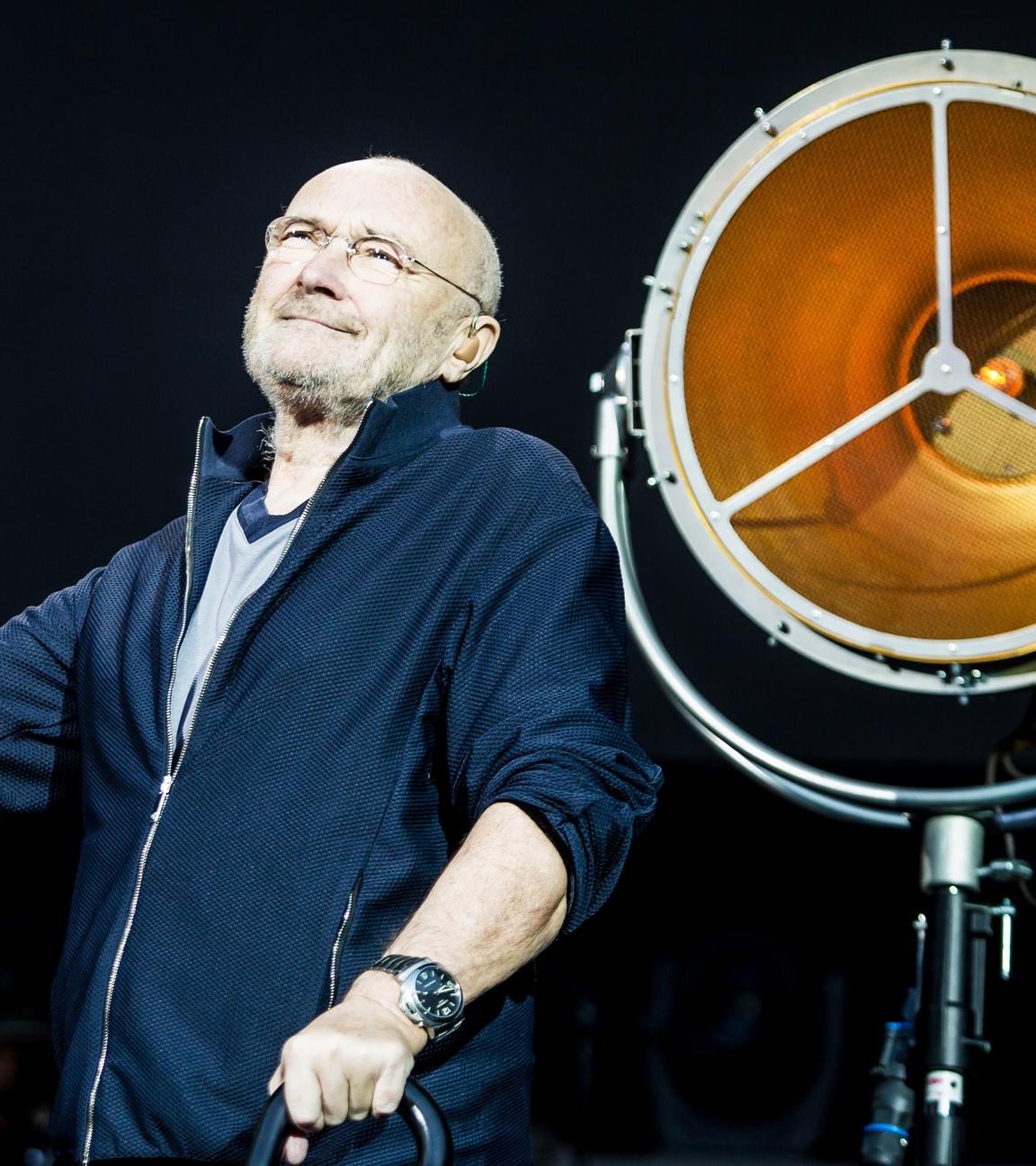 Sänger Phil Collins steht auf der Bühne.