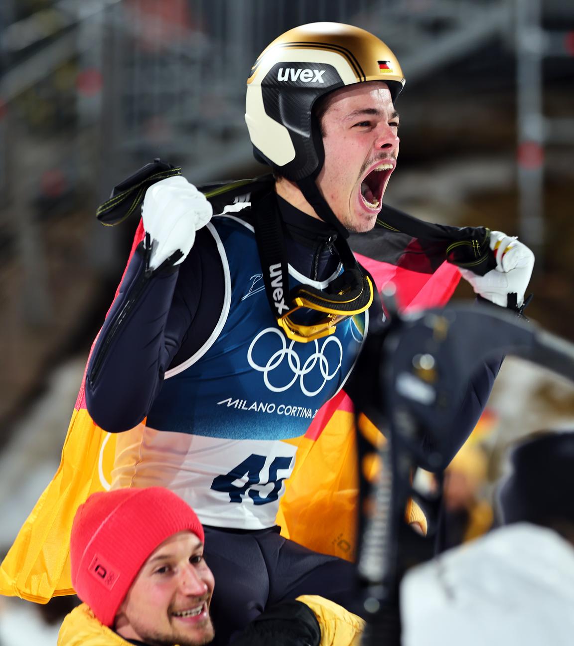 Philipp Raimund (GER) jubelt mit Teamkollegen Felix Hoffmann (GER) nach seinem Sieg auf der Normalschanze, Olympische Winterspiele 2026.