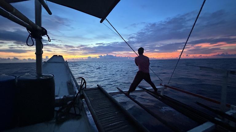Ein Mann steht auf einem Boot und schaut auf das Meer hinaus.