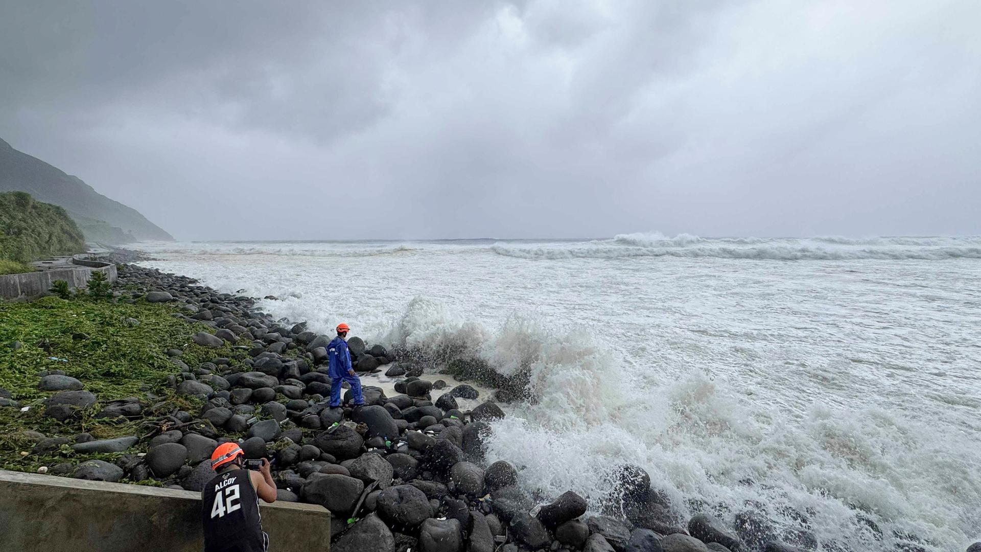 22.09.2025, Philippinen, Basco: Menschen beobachten, wie starke Wellen auf Basco in der Provinz Batanes im Norden der Philippinen einschlagen, als der Taifun "Ragasa" das Gebiet am den 22.09.2025, trifft.