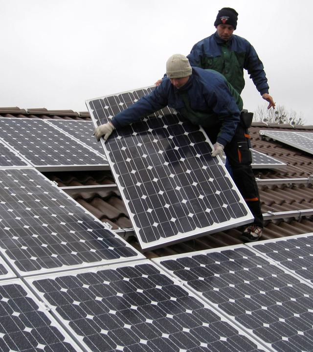 Berlin: Arbeiter installieren eine Photovoltaikanlage auf einem Dach in Falkensee. Archivbild
