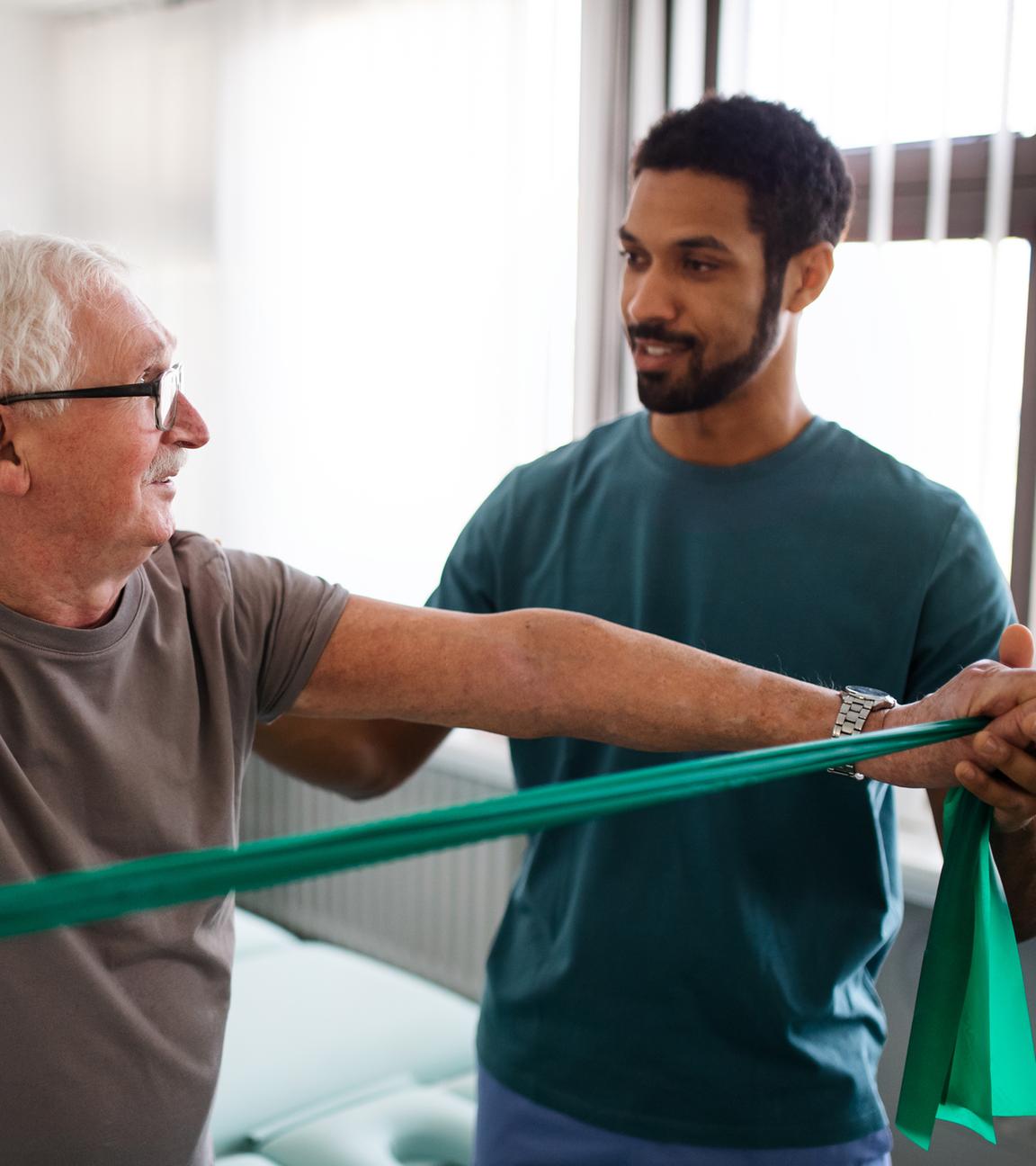 Ein älterer Mann trainiert mit einem Physiotherapeuten.