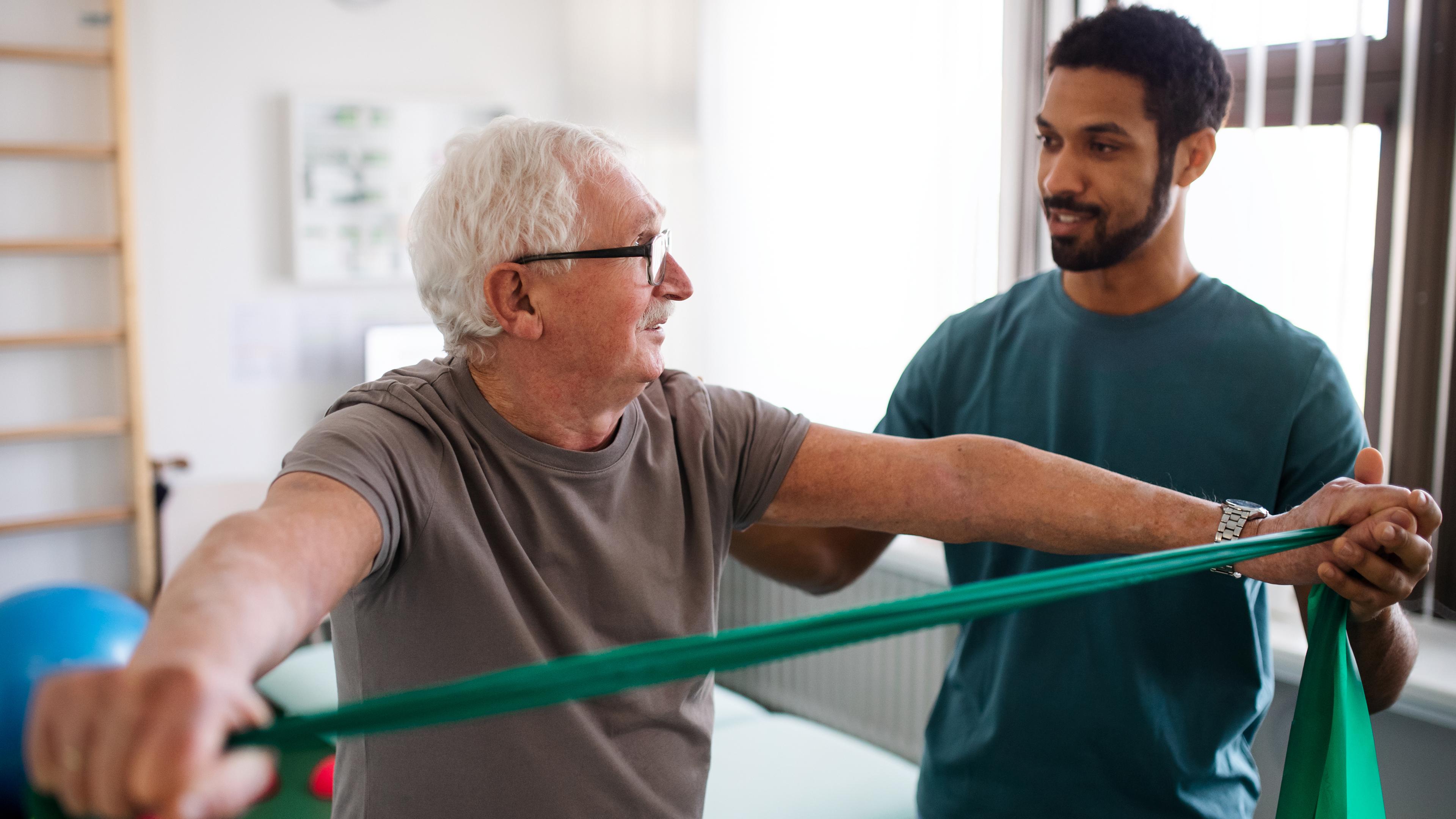Ein älterer Mann trainiert mit einem Physiotherapeuten.