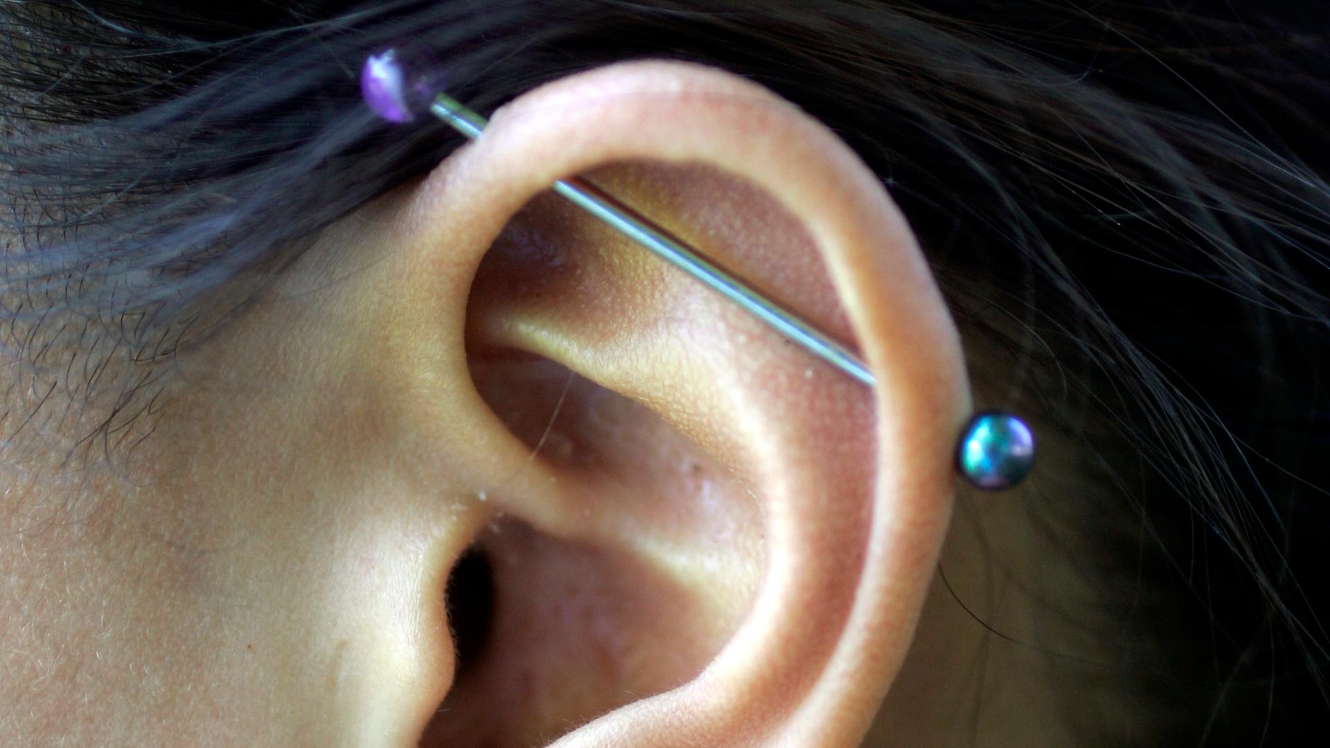 Ohr einer Frau mit diversen Piercings