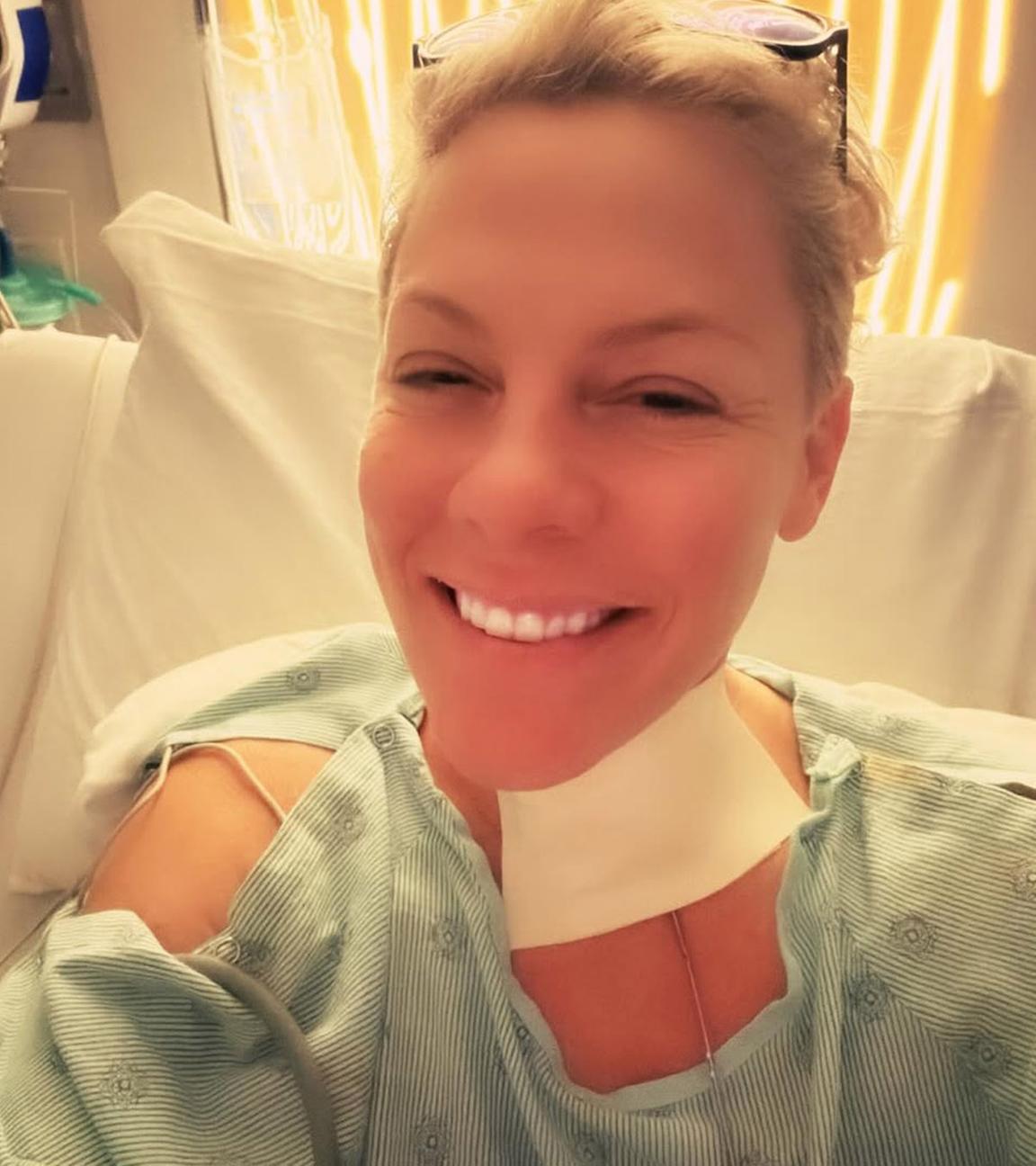 Die Sängerin Pink posiert lächelnd in einem Krankenhausbett, nachdem sie operiert wurde.