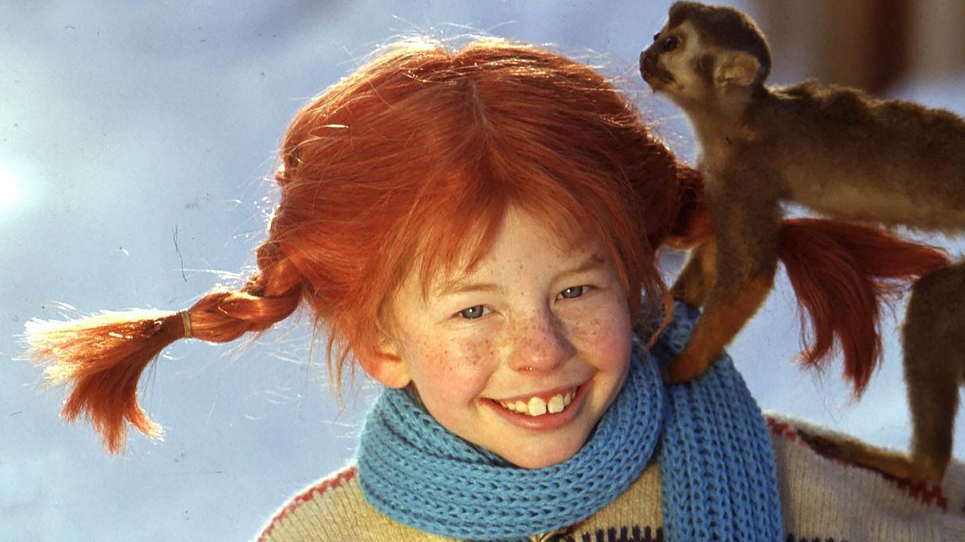 Pippi Langstrumpf (Inger Nilsson) steht im Schnee mit ihrem Affen Herr Nilsson auf dem Arm.