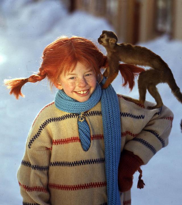 Pippi Langstrumpf (Inger Nilsson) steht im Schnee mit ihrem Affen Herr Nilsson auf dem Arm.