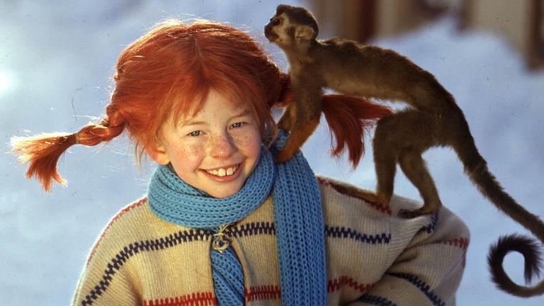 Pippi Langstrumpf steht im Schnee mit ihrem Äffchen Herr Nielson auf dem Arm.