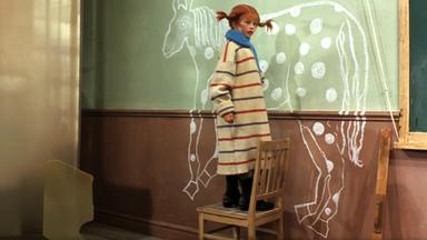 Pippi malt mit Kreide ein Pferd an die Schultafel.