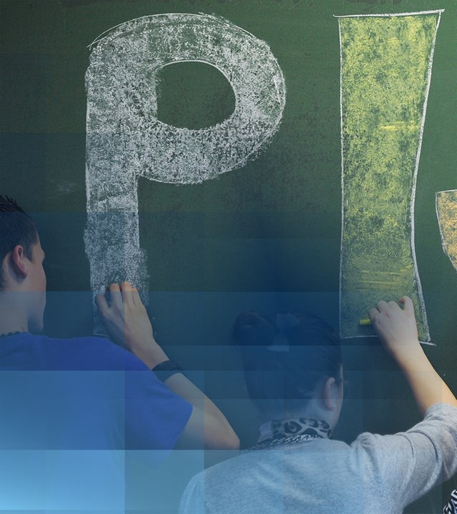 Schülerinnen und Schüler schreiben mit bunter Kreide "PISA" an eine Tafel 