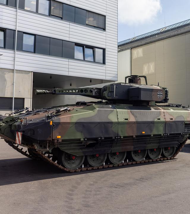 Hessen, Kassel: Ein Schützenpanzer Puma (l) und ein gepanzertes Transport-Kraftfahrzeug, kurz GTK Boxer (2.v.l.), stehen während des Besuchs von Bundesverteidigungsminister Pistorius beim Rüstungshersteller KNDS am Standort Kassel auf dem Gelände.
