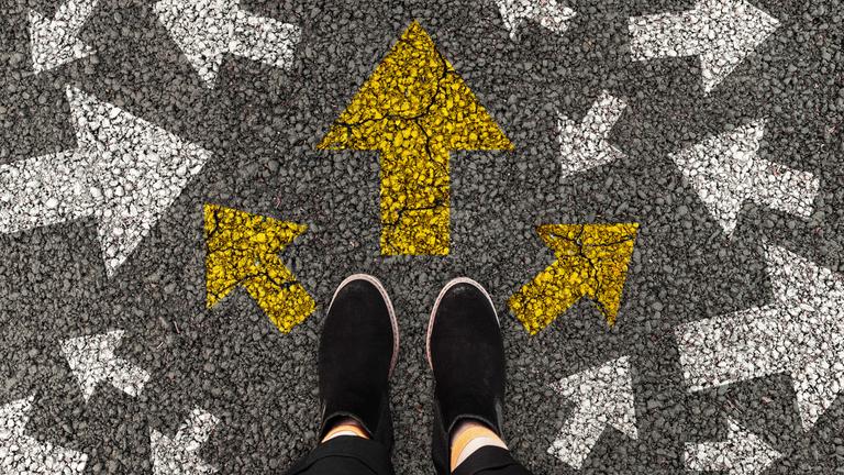 Füße auf einer Straße mit Pfeilmarkierungen