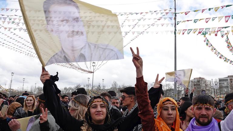 Eine Frau trägt ein Plakat des PKK-Führers Abdullah Öcalan bei der Newroz-Feier in Diyarbakir am 21.05.2025 im türkischen Diyarbakir hoch.
