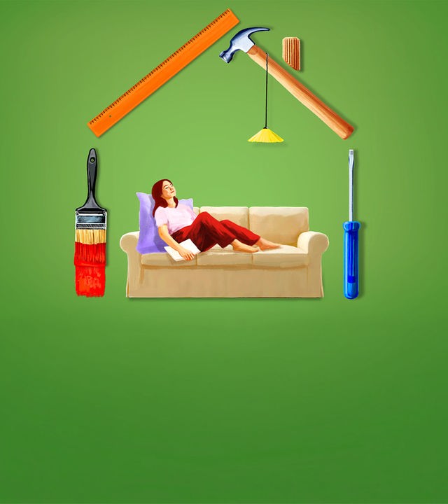 Eine Frau sitzt auf einem Sofa, das in einem schematisch aus Werkzeugen gebauten Haus steht