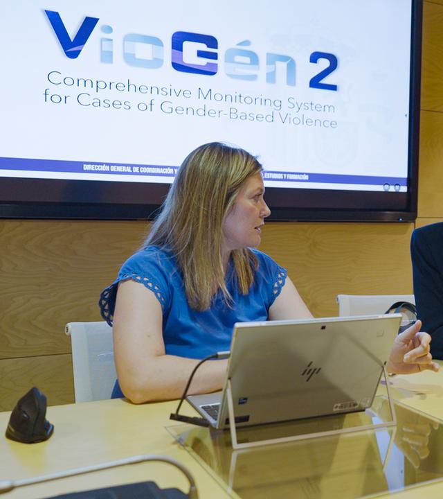 Belén Crego Sánchez von der spanischen Polizei sitzt mit einer Kollegin an einem Konferenztisch. Sie schauen sich an und unterhalten sich. Hinter ihnen auf einem Display steht "VioGén2".