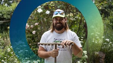 Mann mit Harke im Garten