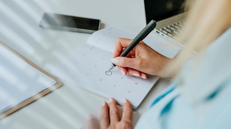 Eine Frau markiert ein Datum in einem Kalender.