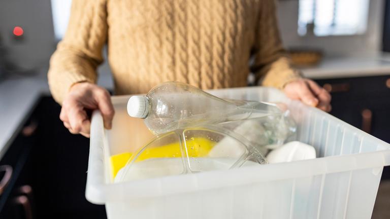 Mann hält eine Box mit Plastikmüll in den Händen.