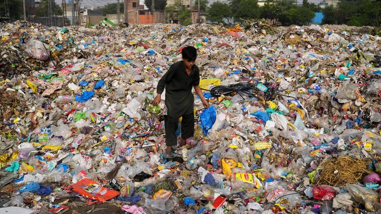 Symbolbild:  Ein Müllsammler sammelt wiederverwertbare Gegenstände, darunter Plastik, auf einer Mülldeponie. 