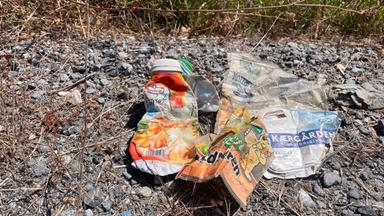 Plastikmüll liegt auf Schotter.