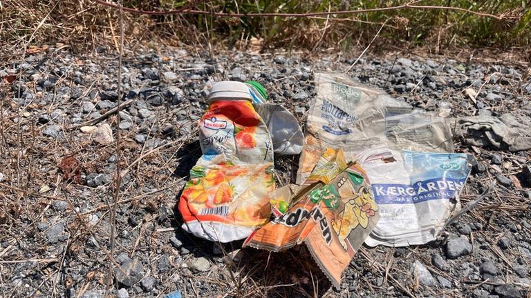Plastikmüll liegt auf Schotter.