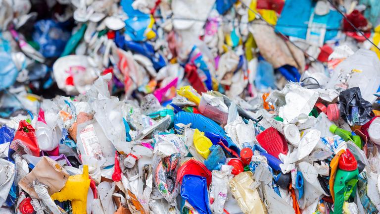 Sortierte Verpackungsabfälle stehen gepresst neben einer Halle, nachdem sie in der Sortieranlage eines Entsorgungsunternehmens getrennt worden sind.
