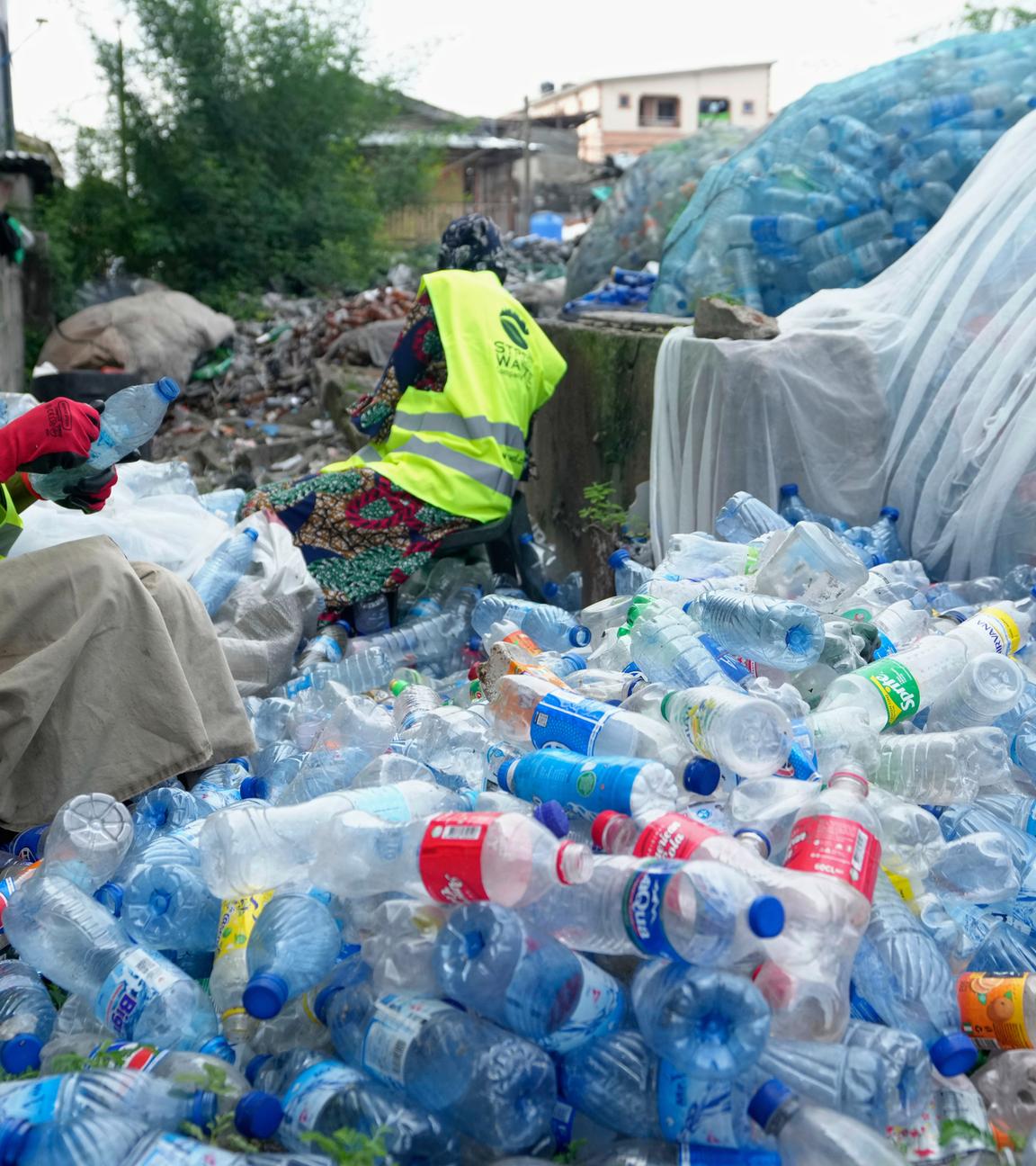 Arbeiterinnen benutzen Rasierklingen, um Etiketten von verschiedenen Softdrink-Plastikflaschen in der Street Waste Company abzukratzen.