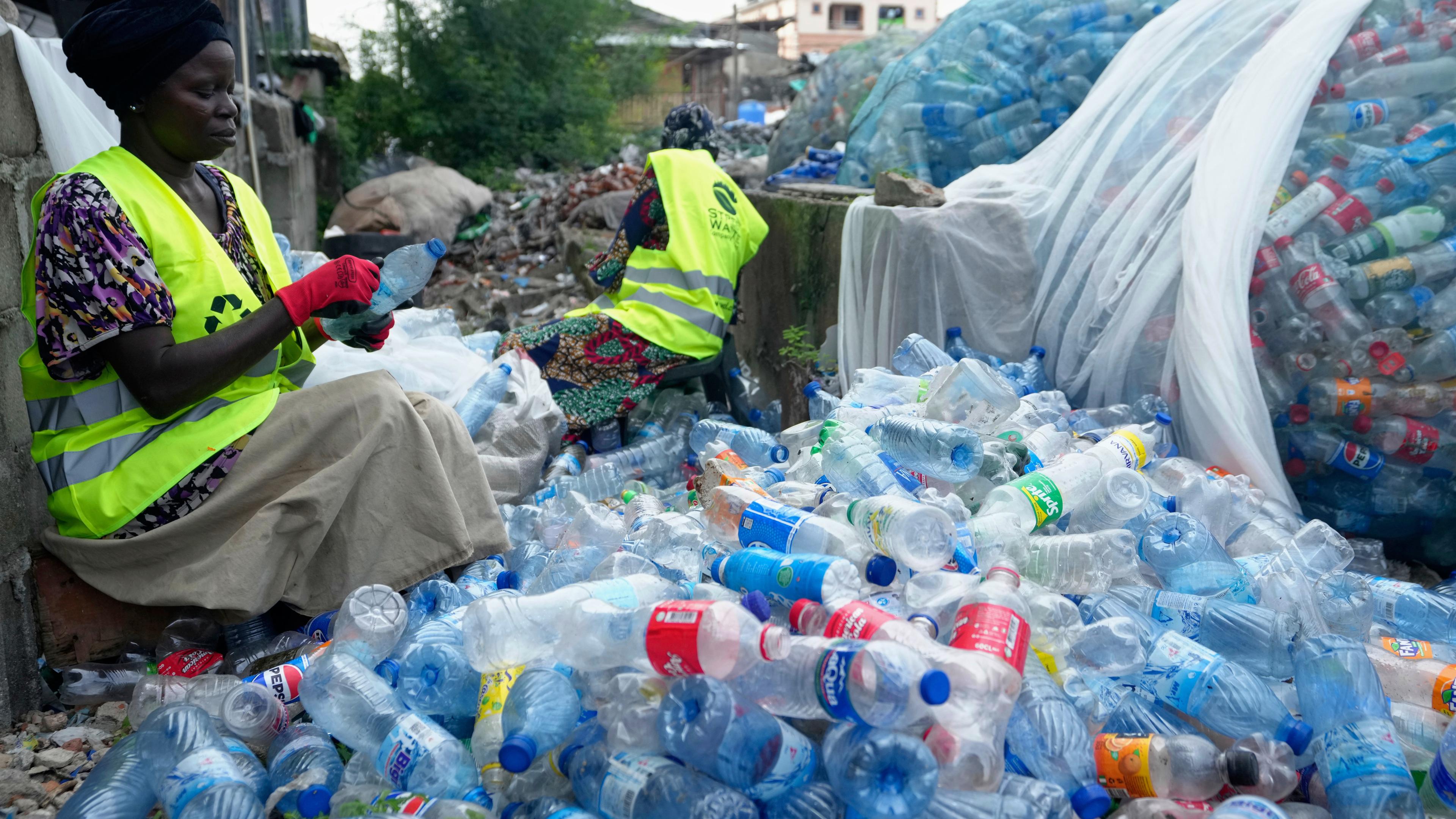 Arbeiterinnen benutzen Rasierklingen, um Etiketten von verschiedenen Softdrink-Plastikflaschen in der Street Waste Company abzukratzen.
