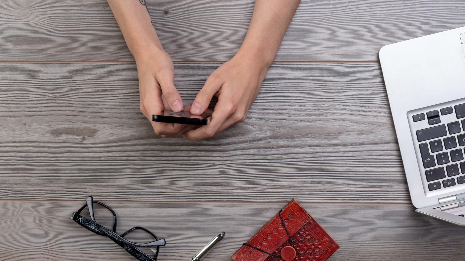 Arbeiter mit Handy und Laptop am Schreibtisch