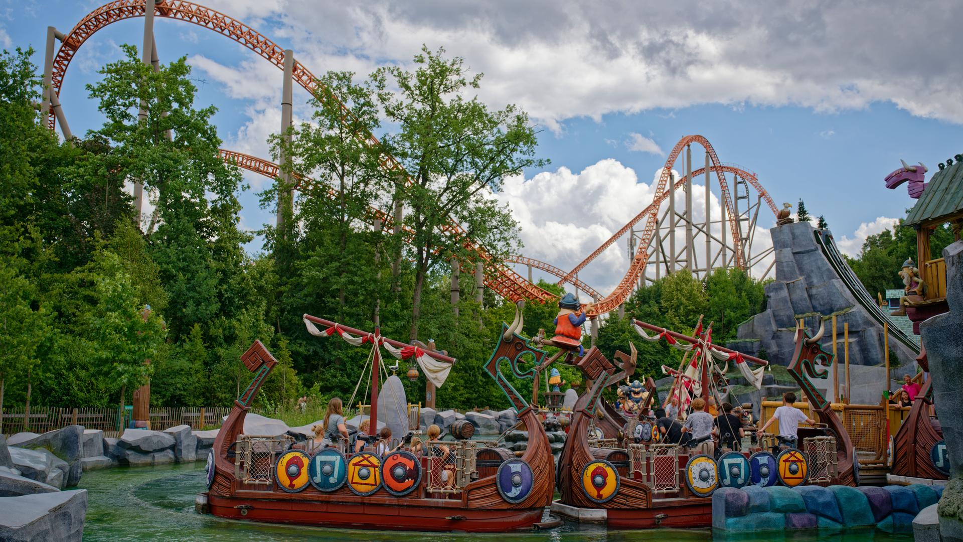 Wikinger-Schiffe treiben im Freizeitpark Plopsaland vor einer Achterbahn im Wasser.