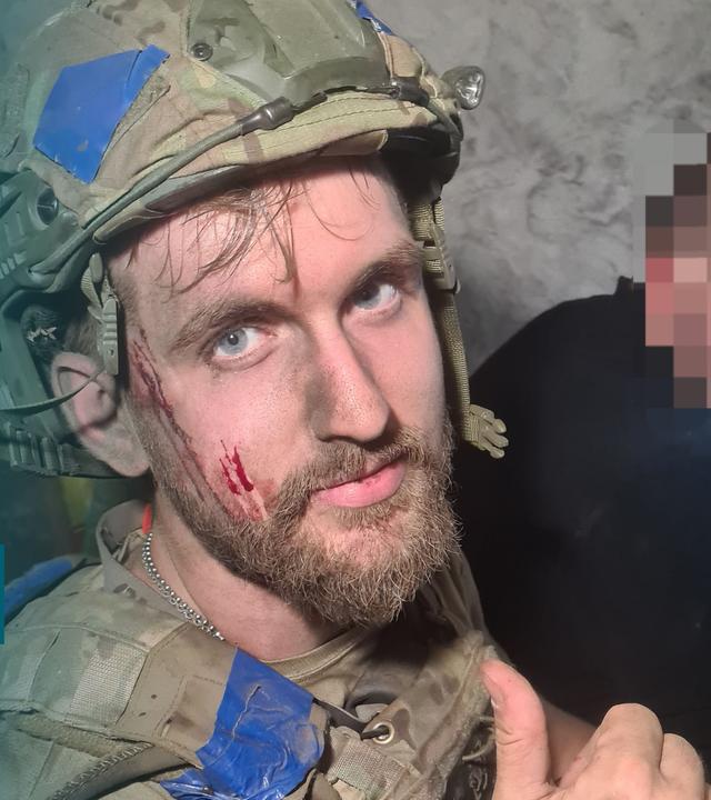 Ein ukrainischer Soldat im Kampfmontur blickt in Richtung Kamera.