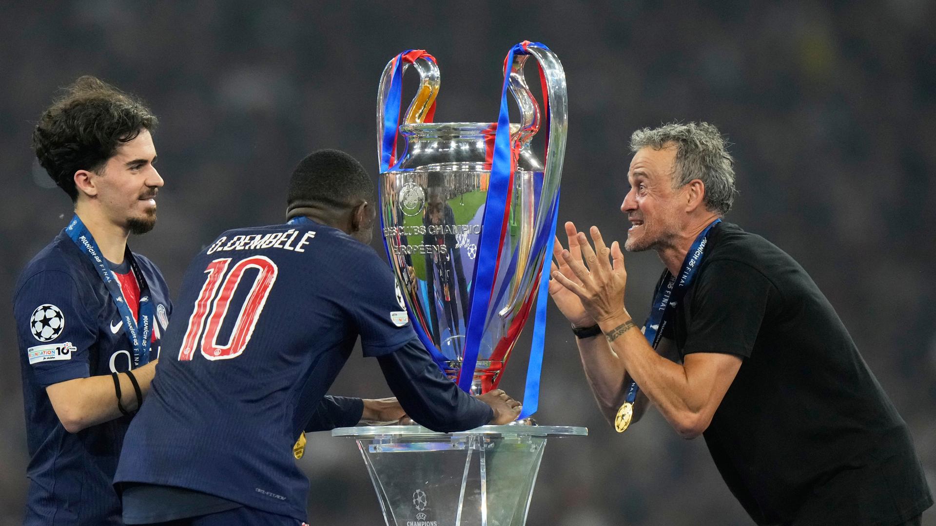 Luis Enrique und Spieler Vitinha (l.) und Ousmane Dembele mit dem Pokal.