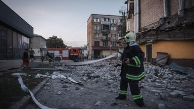 Eine Einsatzkraft der Feuerwehr hält inmitten von Trümmern einen Schlauch in der Hand.