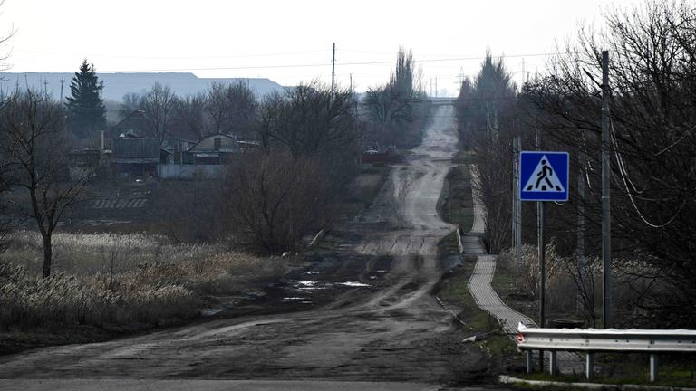 Straße in einem Dorf in der Nähe der Stadt Pokrowsk in der Region Donezk, mit Hügeln aus Minenhalden im Hintergrund