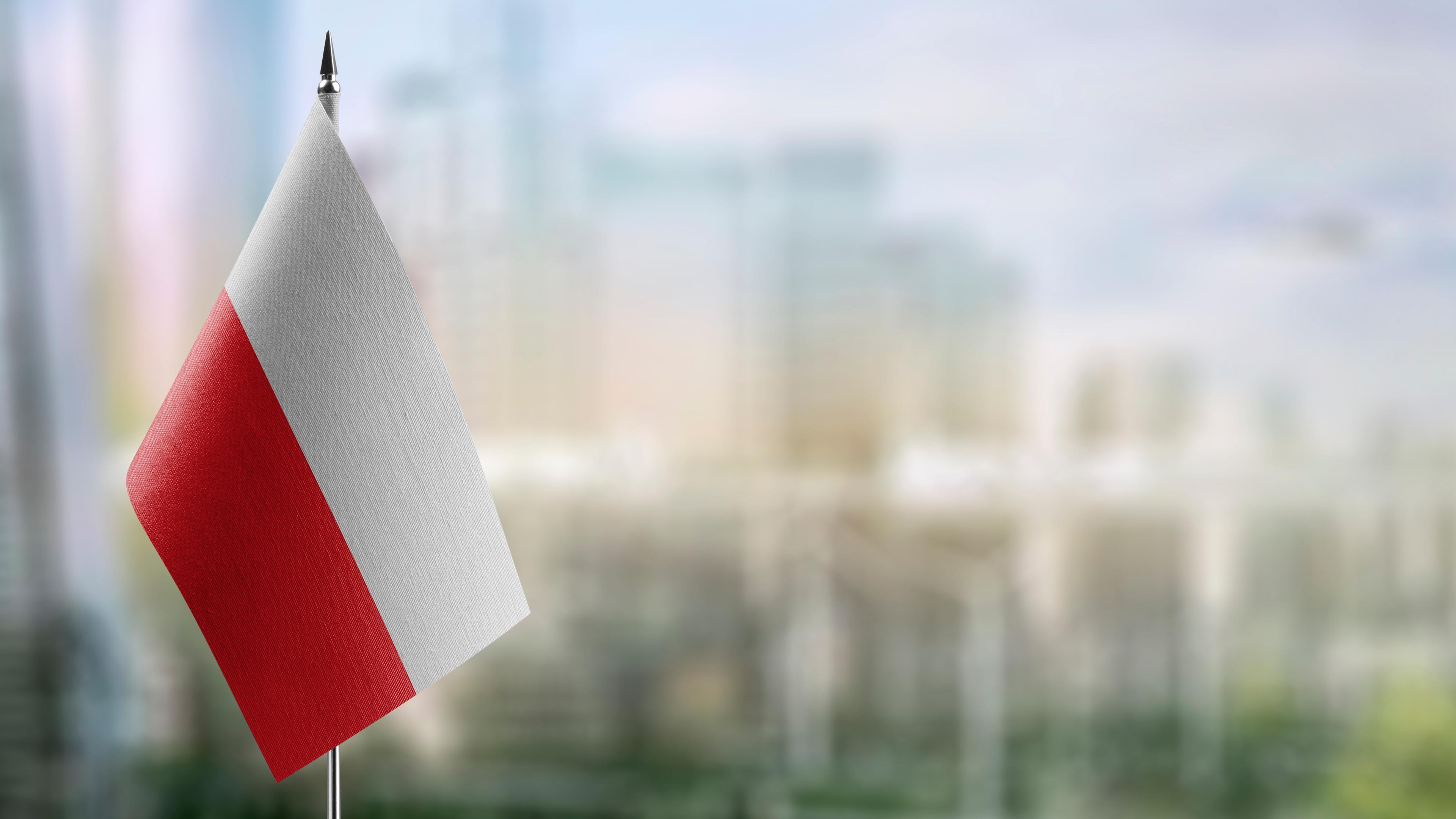 Kleine Flaggen der Polen auf einem abstrakten unscharfen Hintergrund
